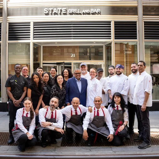 Restaurant staff pose together outside State Grill and Bar, with chefs and servers gathered in front of the entrance.